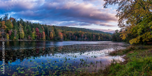 Fotografie Pink and purple clouds hover over the fall colors around the lake shore and are being reflected by the lake at Bays Mountain Park