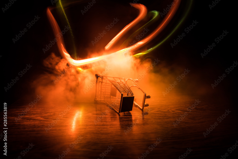 Empty shopping trolley on dark toned foggy background with some copy space. Financial crisis concept.