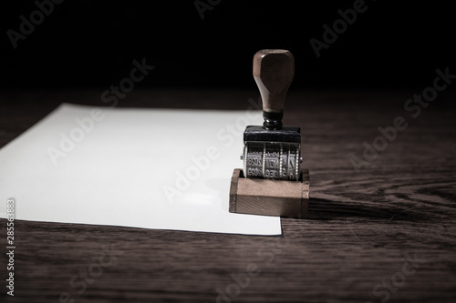 Close up view of rubber date stamper on wooden table with dark toned foggy background. photo
