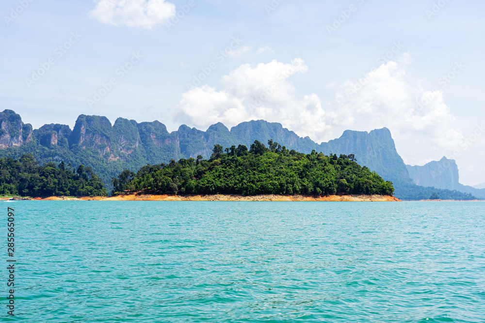 Small green island on lake with mountain range background