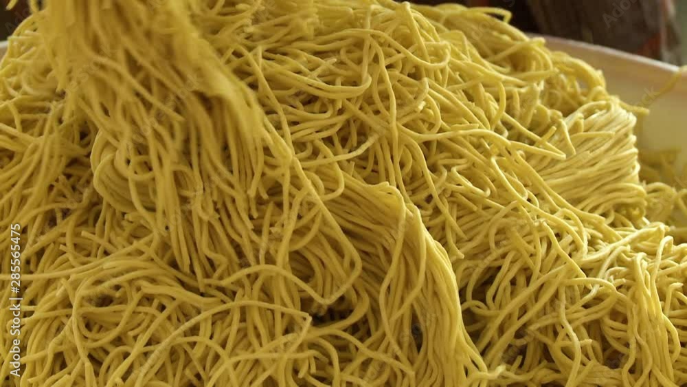 Handheld, medium close up shot of hands mixing a heap of spaghetti. Handheld, medium close up shot of hands mixing a heap of spaghetti.