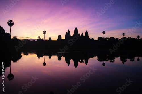 Angkor Wat temple silhouette at dramatic sunrise reflecting in water