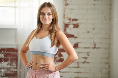 Bilde på lerret Beautiful young blonde fitness model poses in sports bra and pink shorts