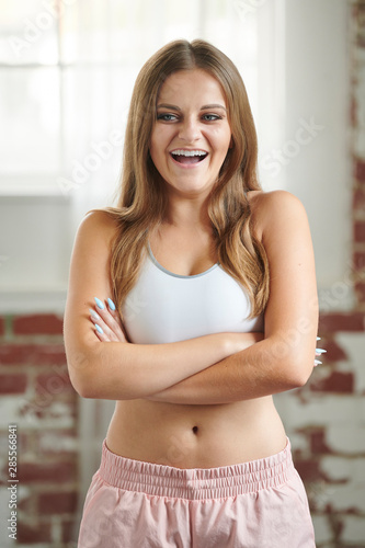 Beautiful young blonde fitness model poses in sports bra and pink shorts