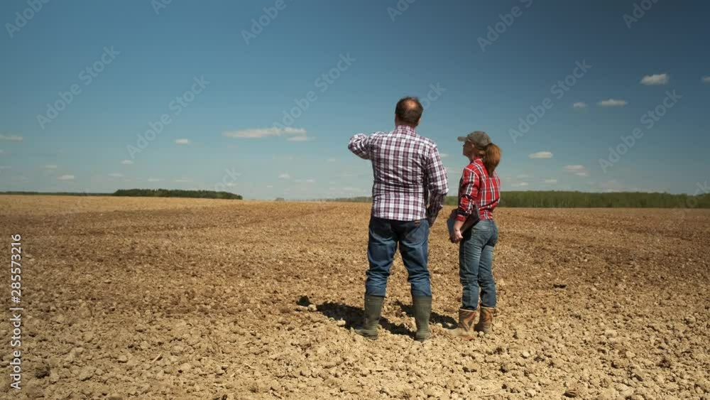 Two businessman farmers talking standing on a plowed field. collaboration, teamwork, family business. Two businessman farmers talking standing on a plowed field. collaboration, teamwork, family business.