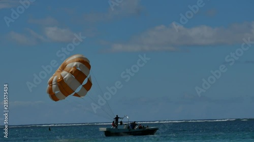 A shot following from the shore of a sport boat that´s going to start to do parasailing, until the moment of take off photo