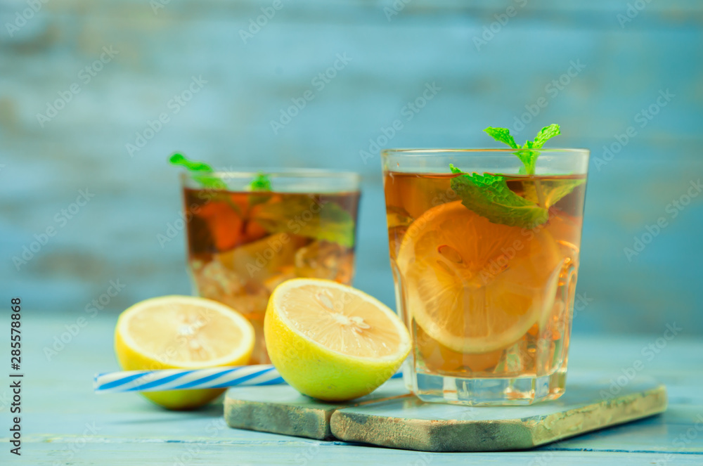 Iced tea with lemon slices and mint on wood background Iced tea with lemon slices and mint on wood background