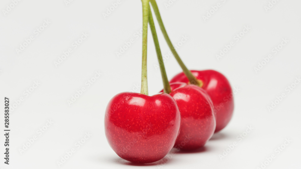 Three red ripe cherry fruits isolated on white background with shadows. Three red ripe cherry fruits isolated on white background with shadows.