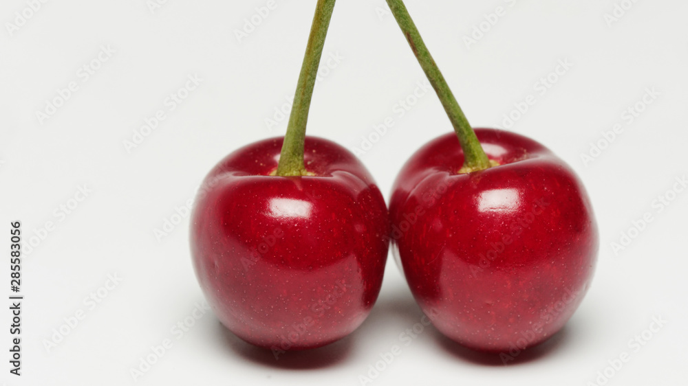 Two red ripe cherry fruits isolated on white background with shadows. Two red ripe cherry fruits isolated on white background with shadows.