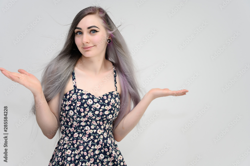 Studio portrait on the waist of a pretty manager girl with long beautiful hair in a beautiful color dress on a white background. He stands straight, smiles, shows with his hands. Studio portrait on the waist of a pretty manager girl with long beautiful hair in a beautiful color dress on a white background. He stands straight, smiles, shows with his hands.