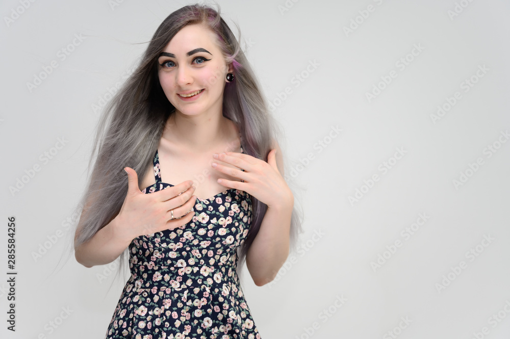 Studio portrait on the waist of a pretty manager girl with long beautiful hair in a beautiful color dress on a white background. He stands straight, smiles, shows with his hands. Studio portrait on the waist of a pretty manager girl with long beautiful hair in a beautiful color dress on a white background. He stands straight, smiles, shows with his hands.
