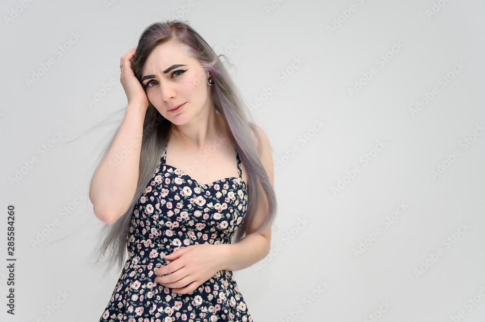 Studio portrait on the waist of a pretty manager girl with long beautiful hair in a beautiful color dress on a white background. He stands straight, smiles, shows with his hands. Studio portrait on the waist of a pretty manager girl with long beautiful hair in a beautiful color dress on a white background. He stands straight, smiles, shows with his hands.