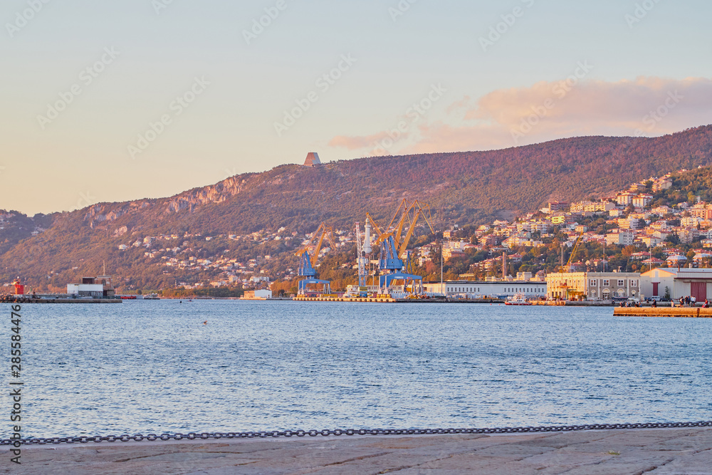 Fototapeta premium Trieste, Italy - September 25, 2018: Port near mountain during sunset in the evening
