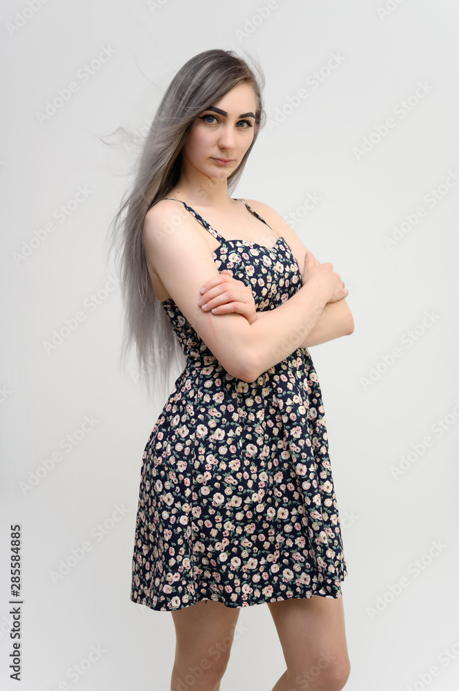 Full length studio portrait of a pretty student girl with long beautiful hair in a beautiful color dress on a white background. He stands straight, smiles, shows with his hands. Full length studio portrait of a pretty student girl with long beautiful hair in a beautiful color dress on a white background. He stands straight, smiles, shows with his hands.