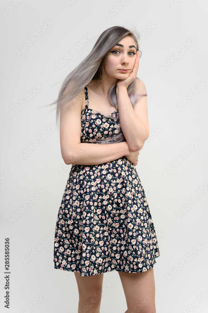 Full length studio portrait of a pretty student girl with long beautiful hair in a beautiful color dress on a white background. He stands straight, smiles, shows with his hands. Full length studio portrait of a pretty student girl with long beautiful hair in a beautiful color dress on a white background. He stands straight, smiles, shows with his hands.