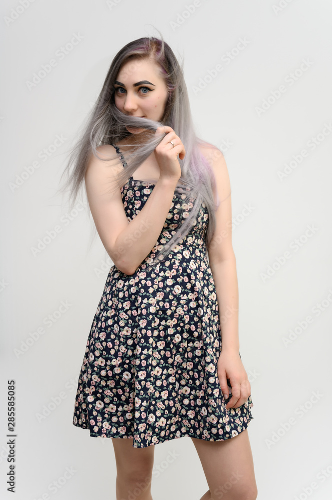 Full length studio portrait of a pretty student girl with long beautiful hair in a beautiful color dress on a white background. He stands straight, smiles, shows with his hands. Full length studio portrait of a pretty student girl with long beautiful hair in a beautiful color dress on a white background. He stands straight, smiles, shows with his hands.