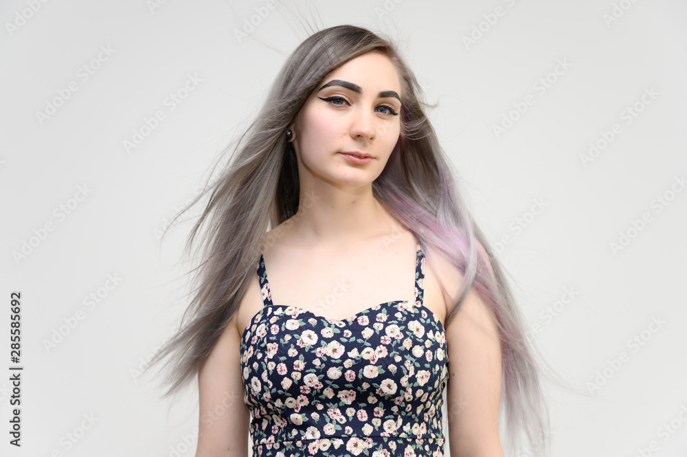 Studio portrait of a pretty student girl with long beautiful hair in a beautiful color dress on a white background. He stands straight, smiles, shows with his hands. Studio portrait of a pretty student girl with long beautiful hair in a beautiful color dress on a white background. He stands straight, smiles, shows with his hands.
