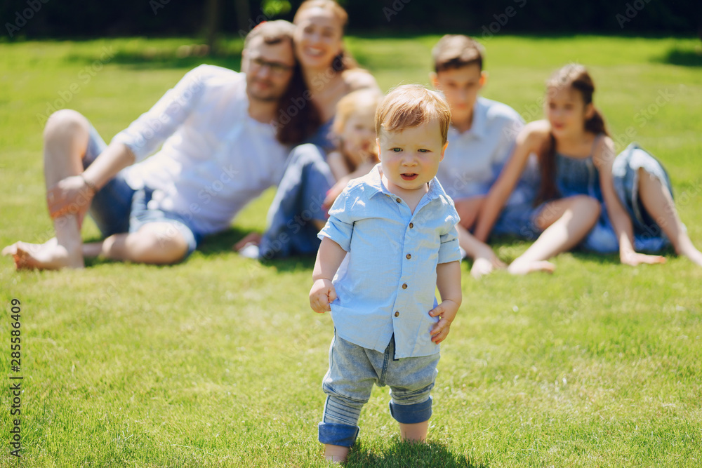 beautiful long-haired mother in a long blue dress in sunny summer forest walks with his beautiful children and handsome man