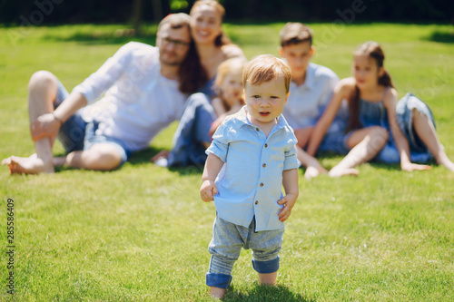 beautiful long-haired mother in a long blue dress in sunny summer forest walks with his beautiful children and handsome man