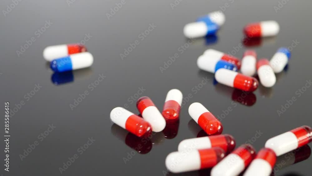 Close up on drug pills and antidepressant medicine capsules in slow motion on a black isolated background. Close up on drug pills and antidepressant medicine capsules in slow motion on a black isolated background.