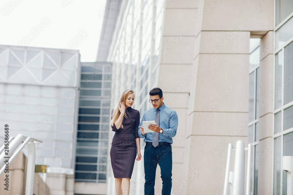 Handsome businessman in a city. Businessman in a glasses. Business couple in a summer city. Man and woman standing with tablet. Pretty blonde in a dress with her parther. Handsome businessman in a city. Businessman in a glasses. Business couple in a summer city. Man and woman standing with tablet. Pretty blonde in a dress with her parther.