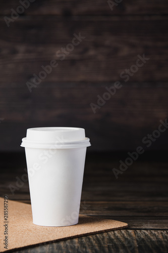 Takeaway cup of coffee on brown wooden background