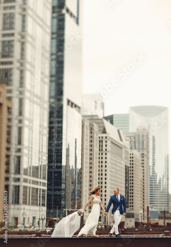 Beautiful bride in a long white dress. Handsome fiance in a blue suit. Couple in a big city © prostooleh