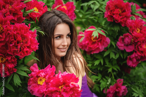 Close up photo of beautiful young woman surrounded by flowers