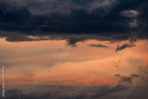 Beautiful sunset sky. Aircraft flying on dark and pastel sky. Art picture of sky at sunrise. Sunrise and fluffy clouds for inspiration background. Nature background. Peaceful and tranquil concept.
