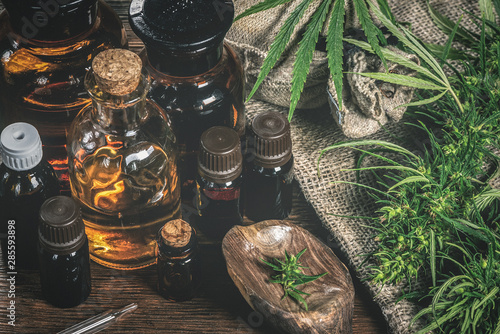 CBD oil bottles and green plant of cannabis on a wooden background. Herbal medicine. photo