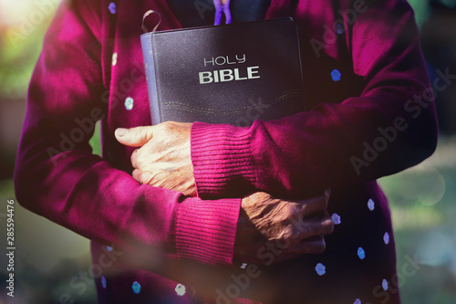 The old woman holding a Bible in nature