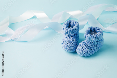 Obraz na płótnie Blue Baby knitted shoes for newborns on blue background, Minimal baby shower, newborn party background, copy space w salonie
