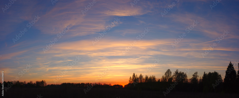 Sunset with clouds over forest silhouette