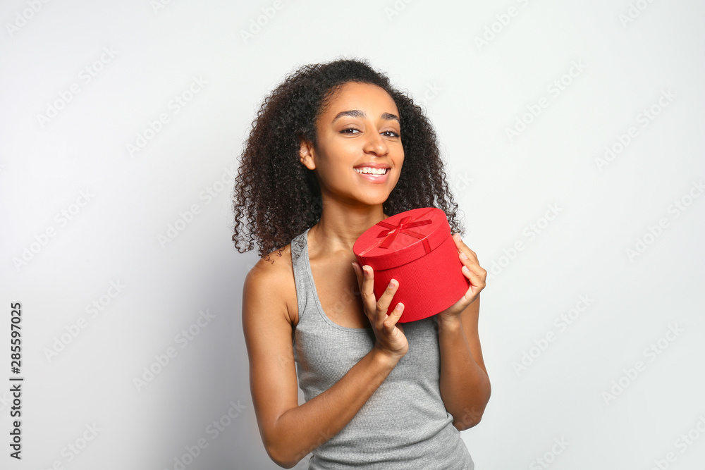 Portrait of beautiful African-American woman with gift box on white background Portrait of beautiful African-American woman with gift box on white background