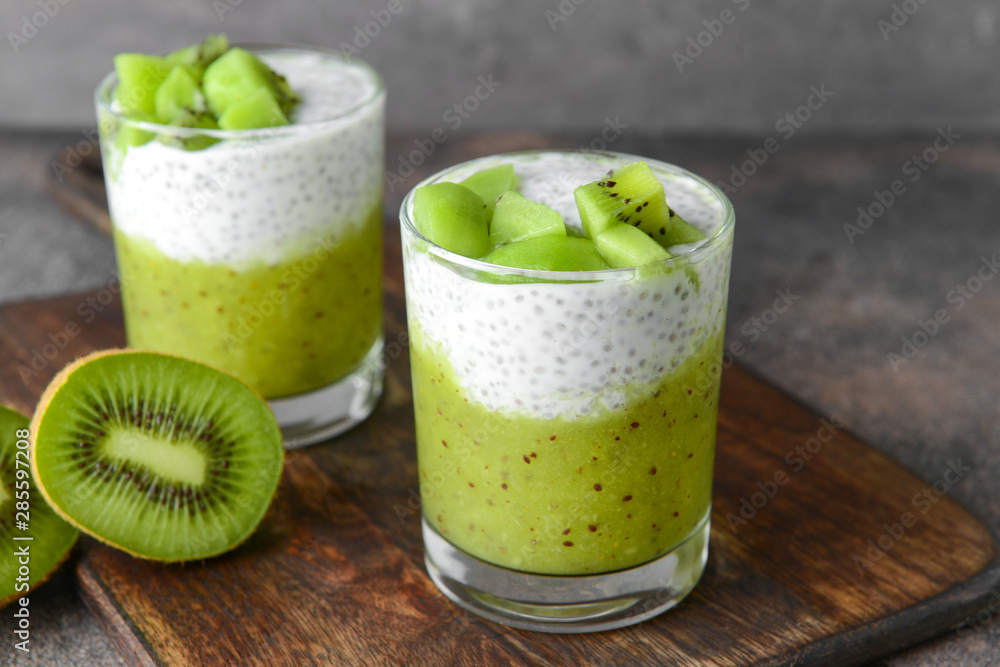 Glasses with tasty kiwi dessert on wooden board Glasses with tasty kiwi dessert on wooden board