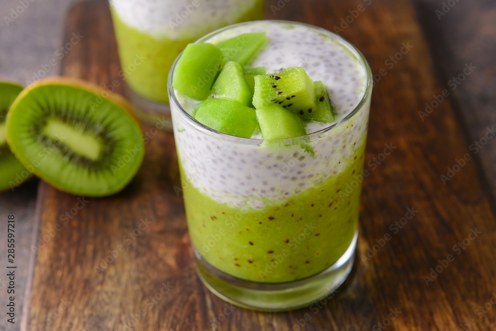 Glass with tasty kiwi dessert on wooden board Glass with tasty kiwi dessert on wooden board