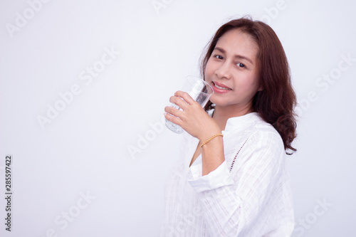 Happy young woman showing drinking glass with water at home.