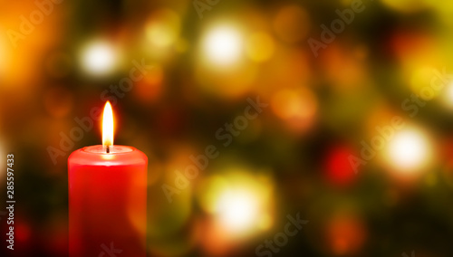 rote kerze vor weihnachtlichem hintergrund mit unscharfen lichtern  weihnachtskarte konzept mit textfreiraum
