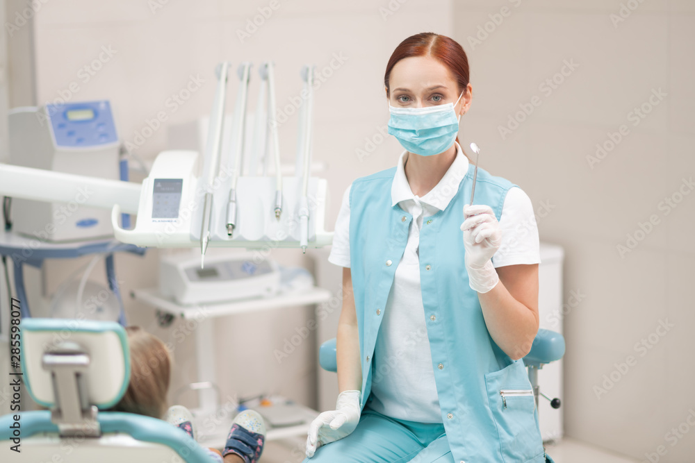 Red-haired child dentist wearing uniform and mask Red-haired child dentist wearing uniform and mask