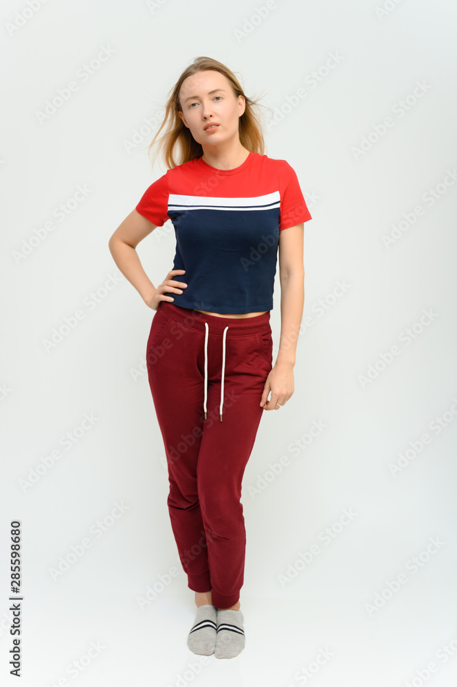 Full length studio portrait of a pretty young happy blonde woman in a tracksuit on a white background. He smiles, talks, shows with his hands, moves, shows emotions. Full length studio portrait of a pretty young happy blonde woman in a tracksuit on a white background. He smiles, talks, shows with his hands, moves, shows emotions.