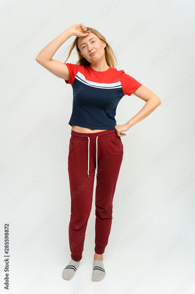 Full length studio portrait of a pretty young happy blonde woman in a tracksuit on a white background. He smiles, talks, shows with his hands, moves, shows emotions. Full length studio portrait of a pretty young happy blonde woman in a tracksuit on a white background. He smiles, talks, shows with his hands, moves, shows emotions.