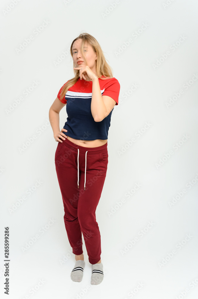 Full length studio portrait of a pretty young happy blonde woman in a tracksuit on a white background. He smiles, talks, shows with his hands, moves, shows emotions. Full length studio portrait of a pretty young happy blonde woman in a tracksuit on a white background. He smiles, talks, shows with his hands, moves, shows emotions.