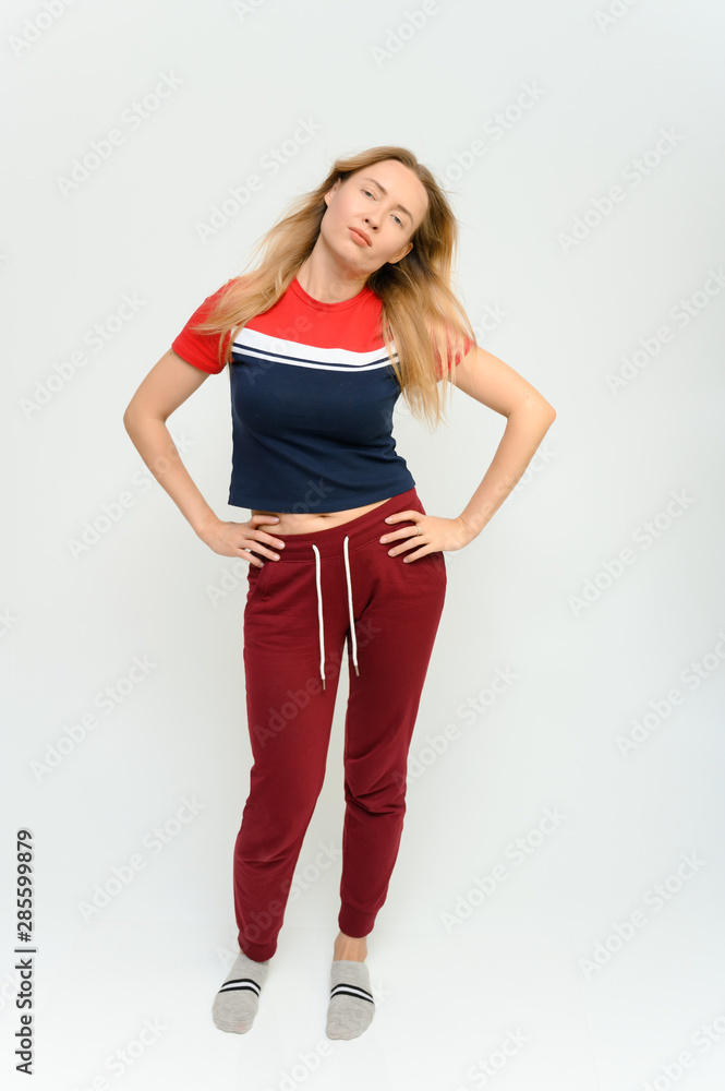Full length studio portrait of a pretty young happy blonde woman in a tracksuit on a white background. He smiles, talks, shows with his hands, moves, shows emotions. Full length studio portrait of a pretty young happy blonde woman in a tracksuit on a white background. He smiles, talks, shows with his hands, moves, shows emotions.