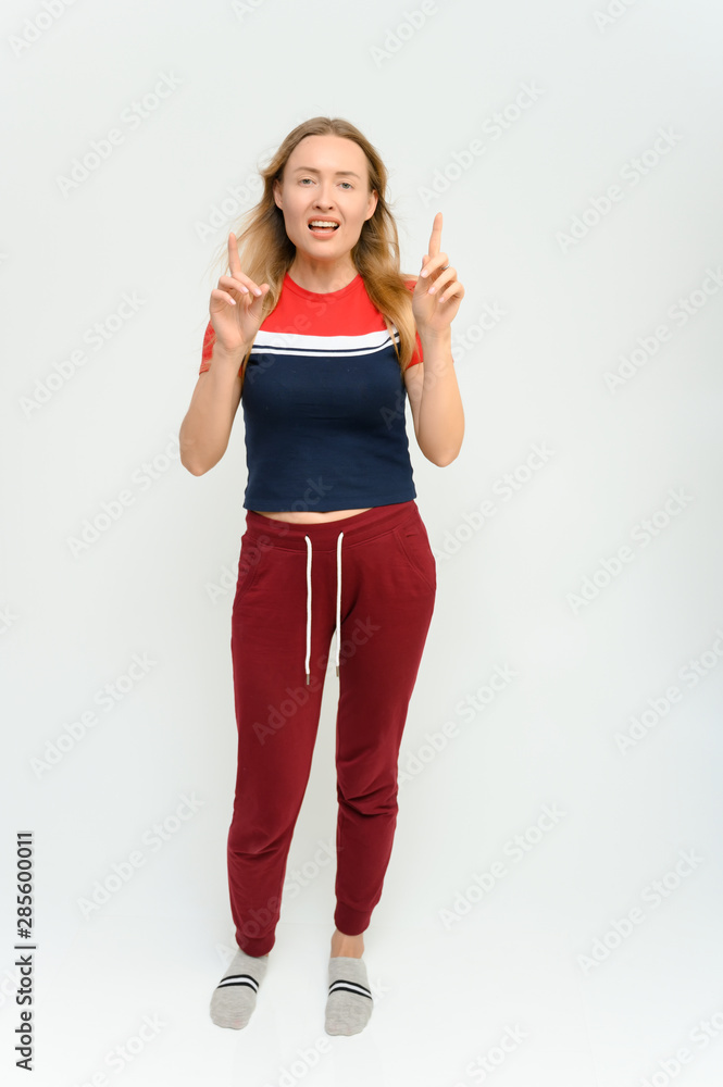 Full length studio portrait of a pretty young happy blonde woman in a tracksuit on a white background. He smiles, talks, shows with his hands, moves, shows emotions. Full length studio portrait of a pretty young happy blonde woman in a tracksuit on a white background. He smiles, talks, shows with his hands, moves, shows emotions.