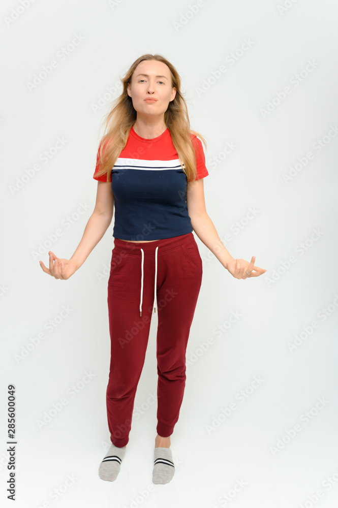 Full length studio portrait of a pretty young happy blonde woman in a tracksuit on a white background. He smiles, talks, shows with his hands, moves, shows emotions. Full length studio portrait of a pretty young happy blonde woman in a tracksuit on a white background. He smiles, talks, shows with his hands, moves, shows emotions.