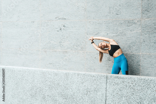 Warming up. Fitness girl doing stretching, morning exercises. Copy space on the left side