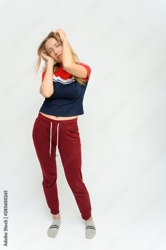 Full length studio portrait of a pretty young happy blonde woman in a tracksuit on a white background. He smiles, talks, shows with his hands, moves, shows emotions. Full length studio portrait of a pretty young happy blonde woman in a tracksuit on a white background. He smiles, talks, shows with his hands, moves, shows emotions.