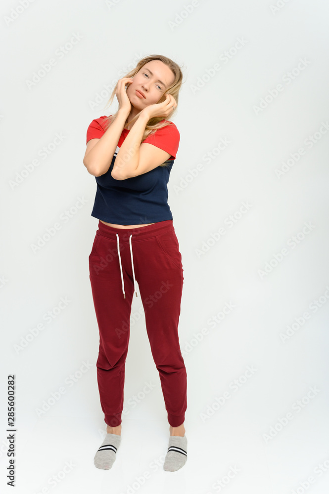 Full length studio portrait of a pretty young happy blonde woman in a tracksuit on a white background. He smiles, talks, shows with his hands, moves, shows emotions. Full length studio portrait of a pretty young happy blonde woman in a tracksuit on a white background. He smiles, talks, shows with his hands, moves, shows emotions.