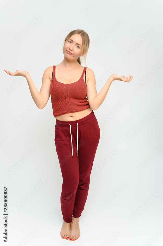 Full length studio portrait of a pretty young happy blonde woman in a tracksuit on a white background. He smiles, talks, shows with his hands, moves, shows emotions. Full length studio portrait of a pretty young happy blonde woman in a tracksuit on a white background. He smiles, talks, shows with his hands, moves, shows emotions.