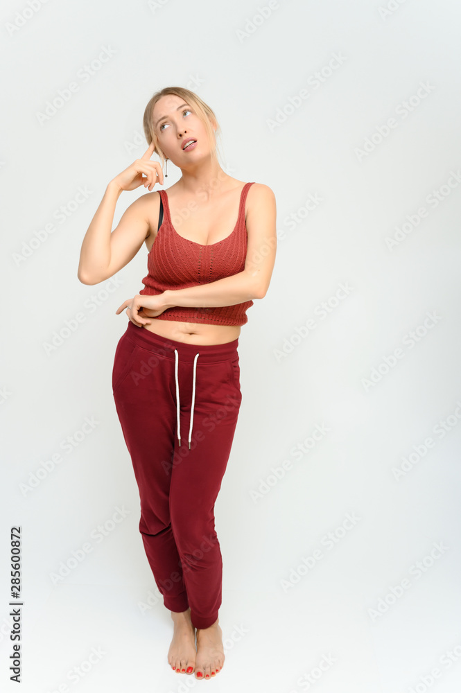 Full length studio portrait of a pretty young happy blonde woman in a tracksuit on a white background. He smiles, talks, shows with his hands, moves, shows emotions. Full length studio portrait of a pretty young happy blonde woman in a tracksuit on a white background. He smiles, talks, shows with his hands, moves, shows emotions.